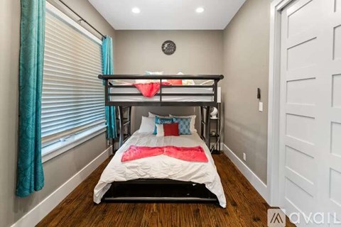 A bedroom with a bunk bed and a window with blue curtains.
