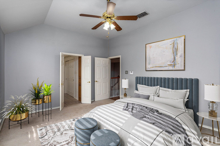 A bedroom with a large bed, a ceiling fan, and a painting on the wall.