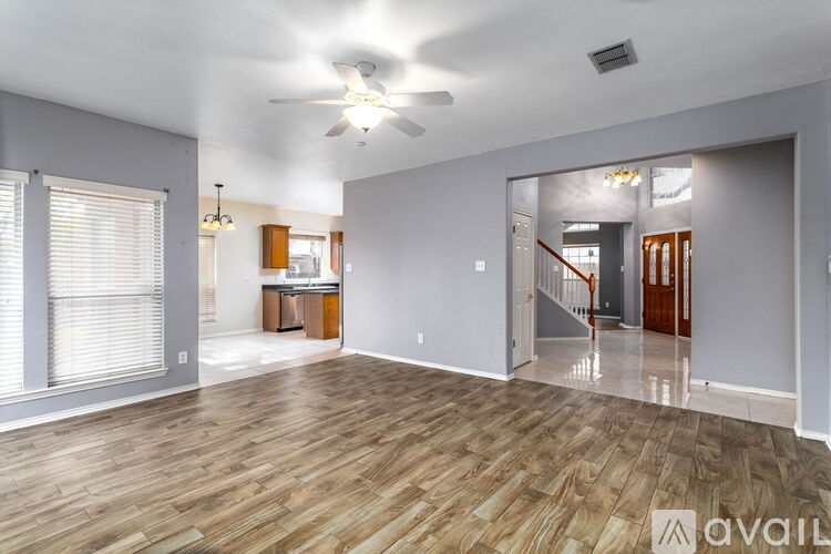A spacious room with wooden flooring and a ceiling fan.