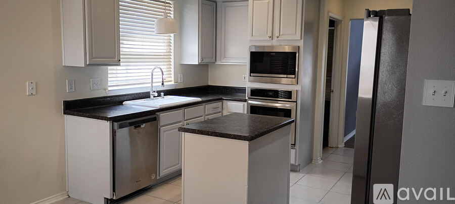 A kitchen with white cabinets and a black countertop.