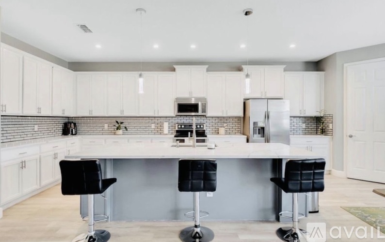 A modern kitchen with a bar area and black stools.