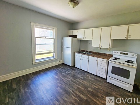 A kitchen with white appliances and wooden floors.