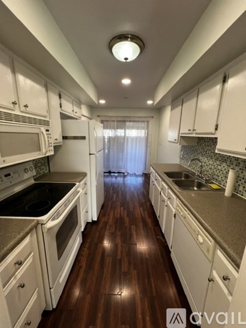 A kitchen with white cabinets and a wooden floor.