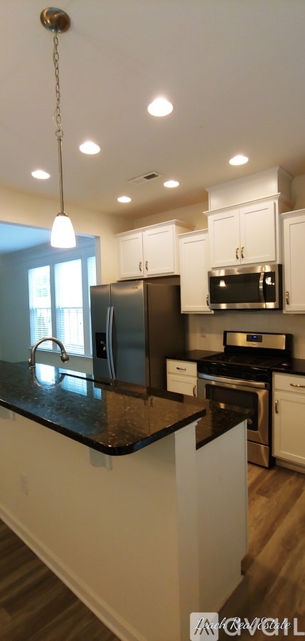 A kitchen with white cabinets and a black counter top.