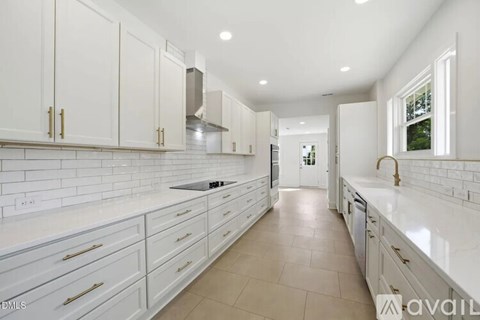 A modern kitchen with white cabinets and a long countertop.