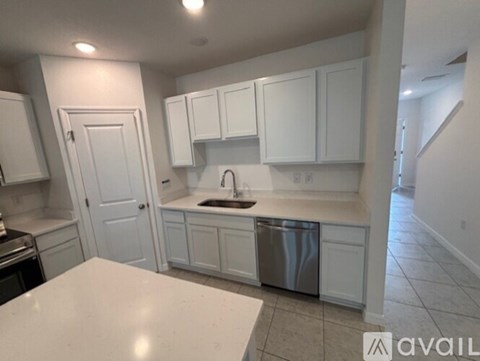 A kitchen with white cabinets and a stainless steel dishwasher.