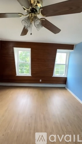 A room with a ceiling fan and wooden flooring.