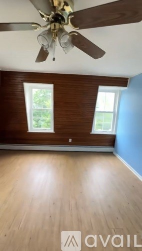 A room with a ceiling fan and wooden flooring.