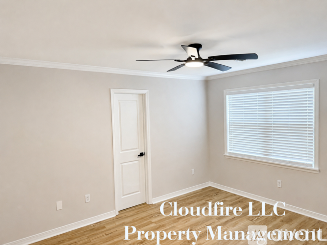 A room with a ceiling fan and a window with blinds.