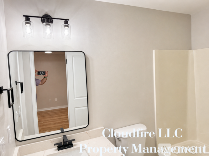 A bathroom with a mirror and lights above it.