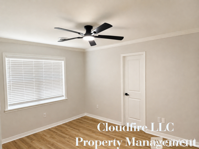 A room with a ceiling fan and a window with blinds.