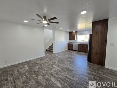 A spacious room with a ceiling fan and wood flooring.