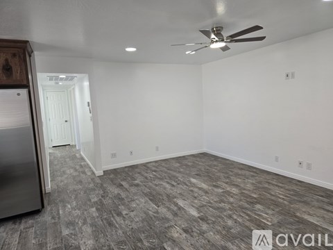 A spacious room with a ceiling fan and a grey carpet.