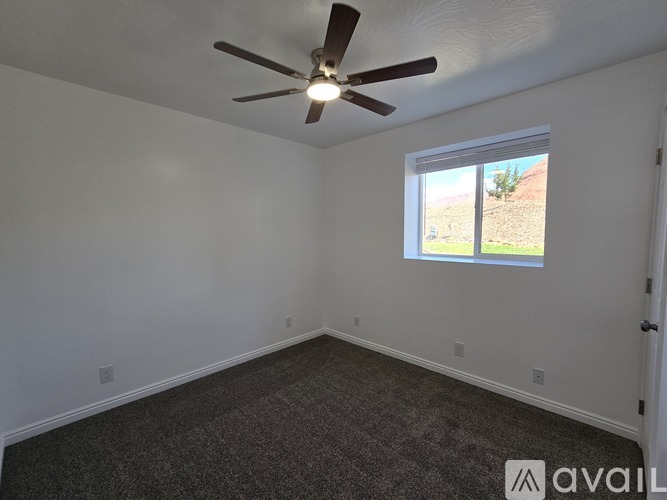 A room with a ceiling fan and a window showing an outdoor view.