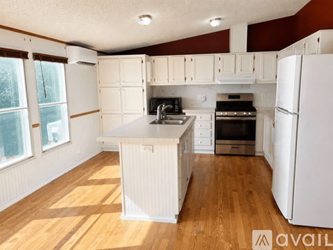 A kitchen with white cabinets and a wooden floor.