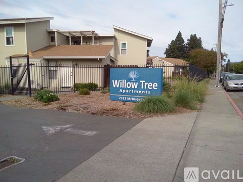 A sign for Willow Tree Apartments is in front of some houses.