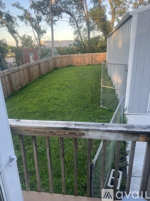 A backyard with a wooden fence and a green lawn.