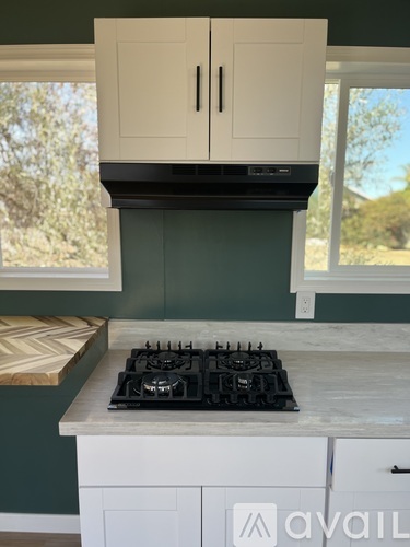 A kitchen with a white stove top oven and cabinets.