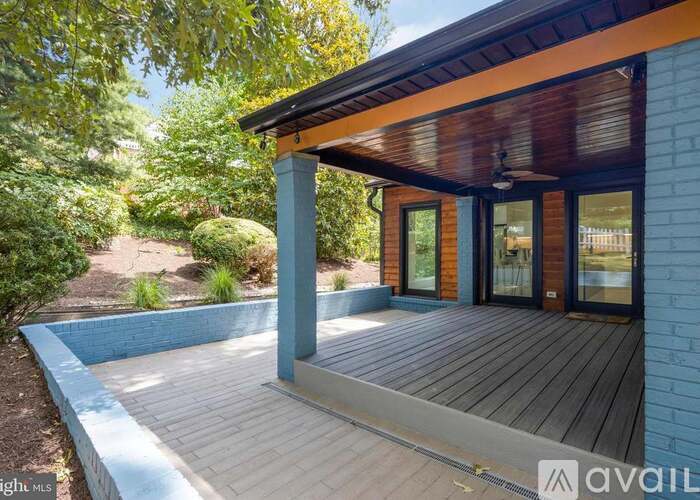 A blue house with a wooden deck and a pool.