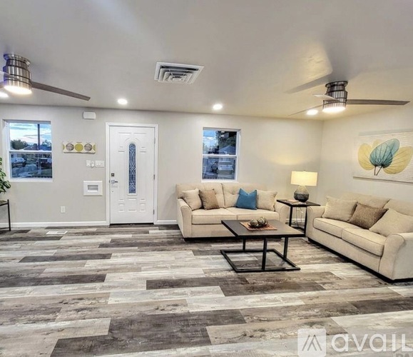 A living room with a white couch, a coffee table, and a ceiling fan.