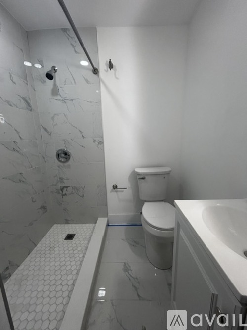 A bathroom with a marble shower and a toilet.