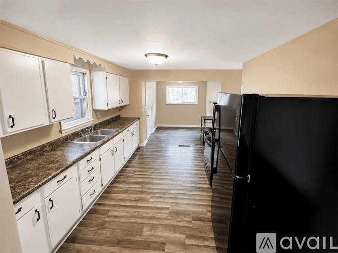 A kitchen with white cabinets and a black refrigerator.