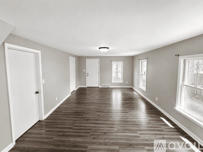 A spacious room with wooden flooring and white walls.