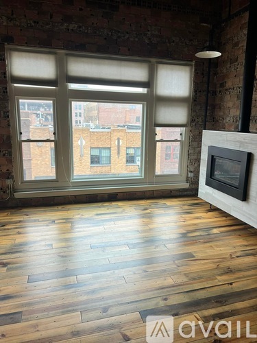 A room with a fireplace and a large window overlooking a city.