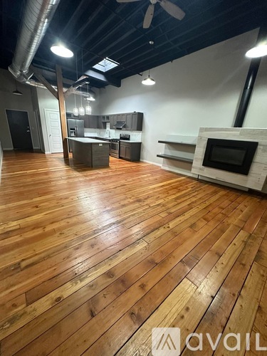 A room with wooden floors and a kitchen area.
