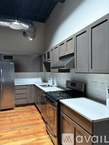 A kitchen with wooden floors and a stainless steel refrigerator.