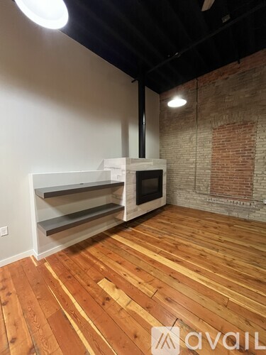 A room with a white wall and a brick wall with a wooden floor and a white microwave.