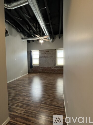 A room with wooden floors and exposed ceiling pipes.