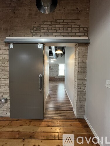 A grey door with a handle is in the middle of a hallway.