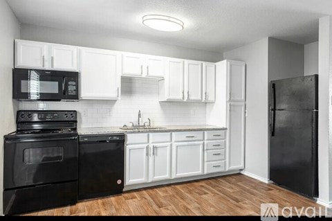 A kitchen with black appliances and white cabinets.