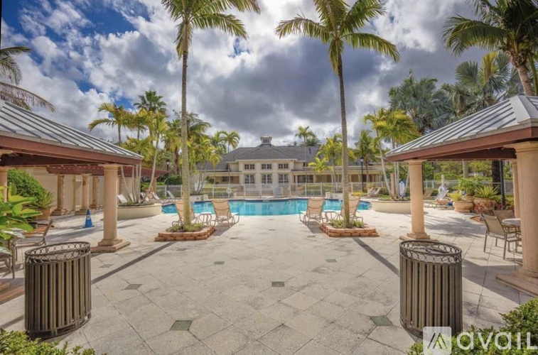 A pool surrounded by palm trees and a gazebo.