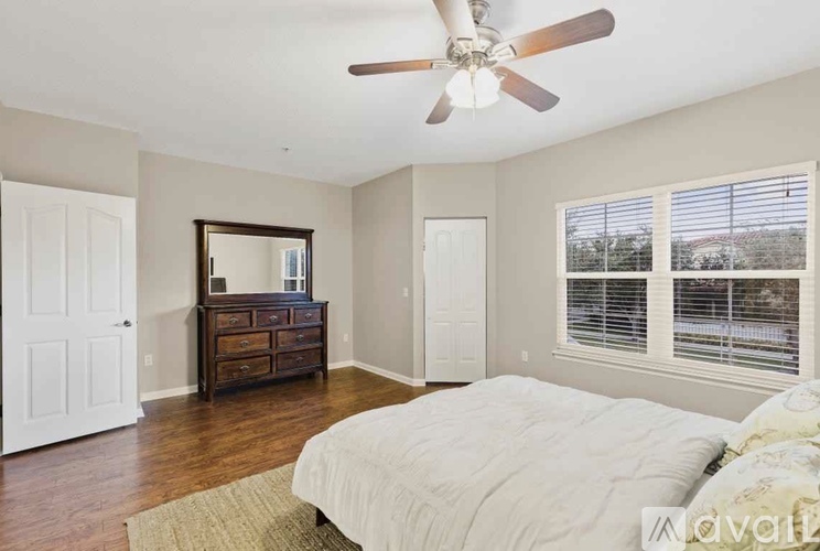 A bedroom with a large bed, a dresser, and a ceiling fan.