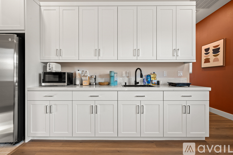 A kitchen with white cabinets and a refrigerator.