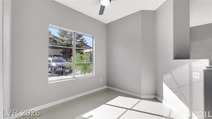 A room with a large window and a view of a street with cars and trees.