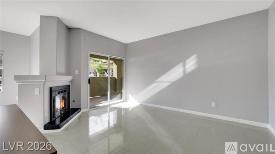 A spacious living room with a fireplace and a view of the outdoors through a glass door.