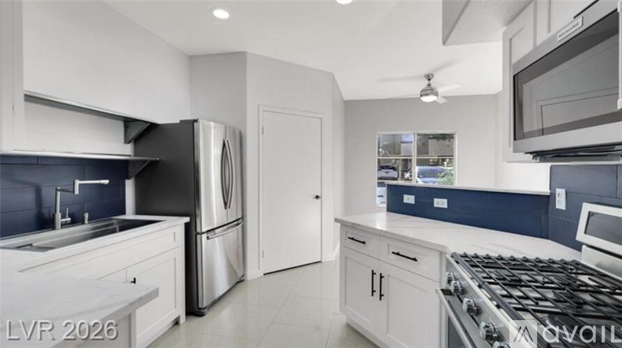 A modern kitchen with white cabinets and stainless steel appliances.