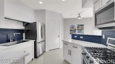 A modern kitchen with white cabinets and stainless steel appliances.