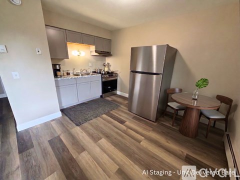 A kitchen with a refrigerator, sink, and dining table.