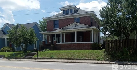 A two-story house with a red brick facade and white trim.