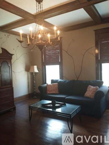 A living room with a black couch and a chandelier.