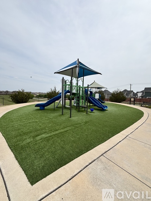 A playground with a blue and white canopy and a green slide.