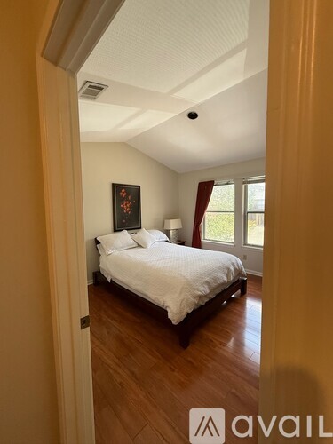 A bedroom with a bed, wooden floors, and a painting on the wall.