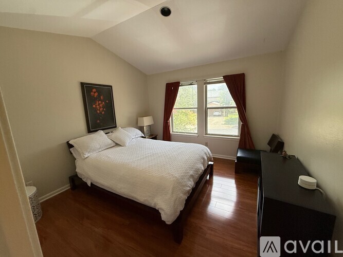 A bedroom with a bed, nightstand, and window.