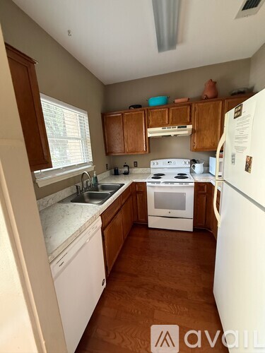A kitchen with white appliances and wooden cabinets.