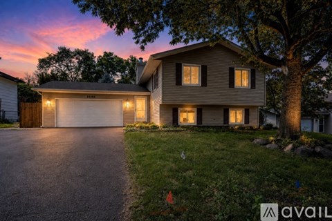 A house with a driveway and garage is lit up at dusk.
