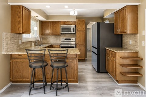 A kitchen with wooden cabinets and a black refrigerator.